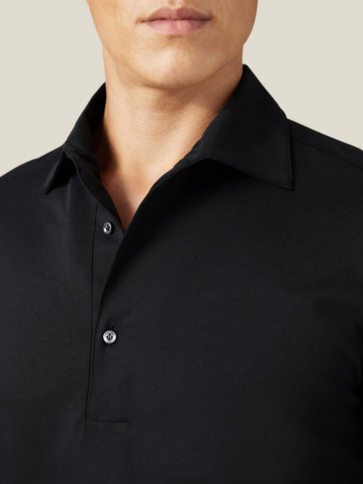 Close-up of the Black Silk-Cotton Polo on a model, showing the detail of the one-piece collar and mother-of-pearl buttons.