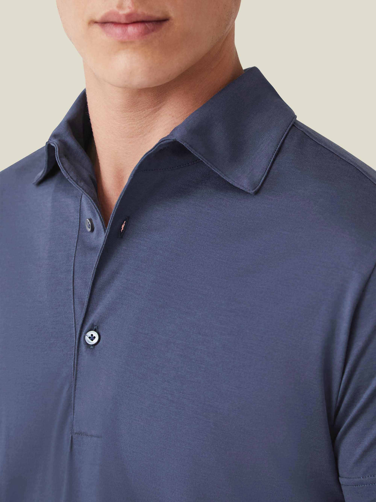 A close-up of a man wearing the Luca Faloni silk-cotton polo in ocean blue, showing the detail of the one-piece collar.