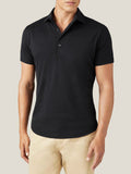 Front view of a model wearing the Luca Faloni black short-sleeved silk-cotton polo with light coloured trousers.