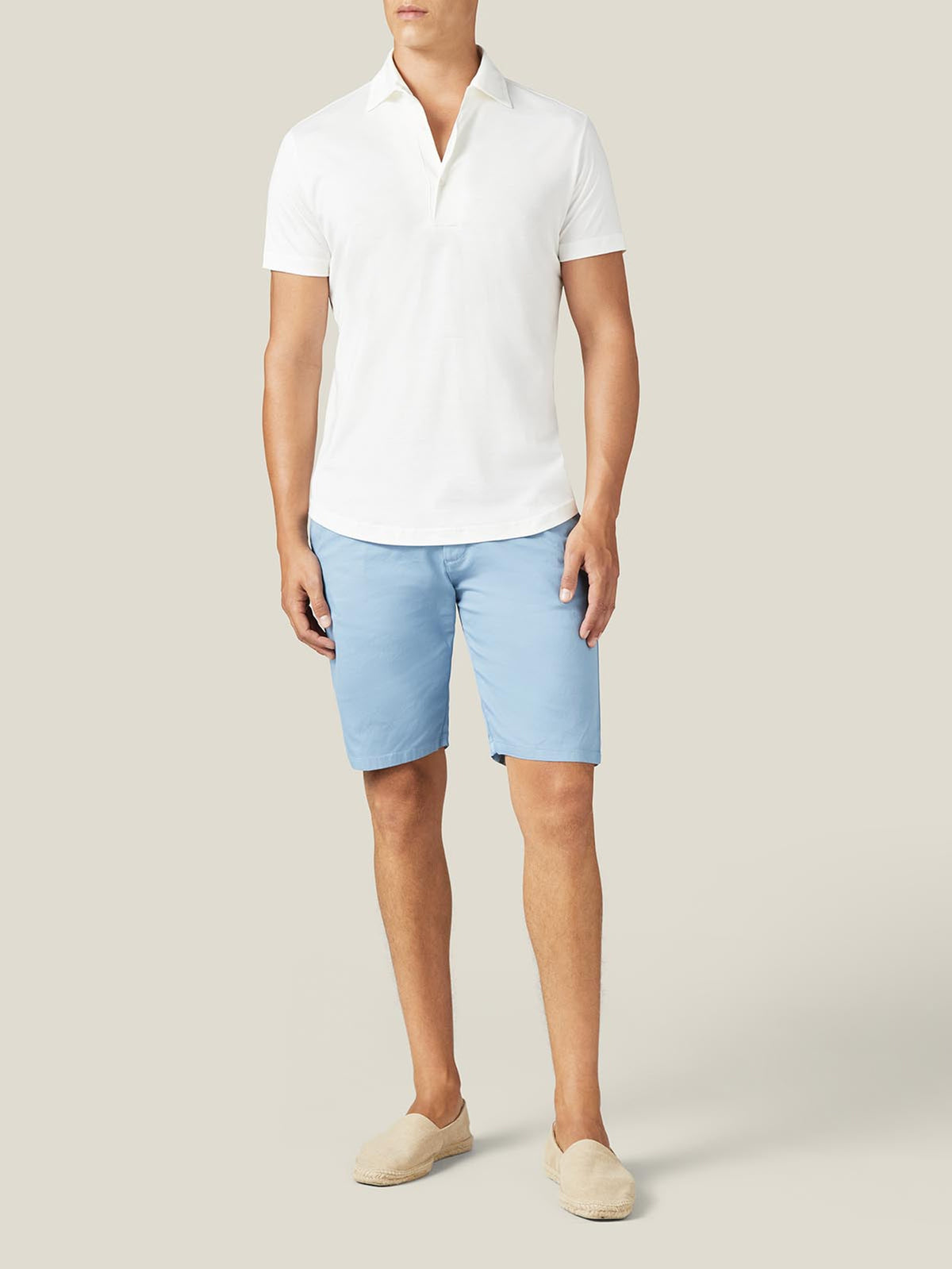 Model wears the white Silk-Cotton Short-sleeved Polo with light blue shorts and cream espadrilles.