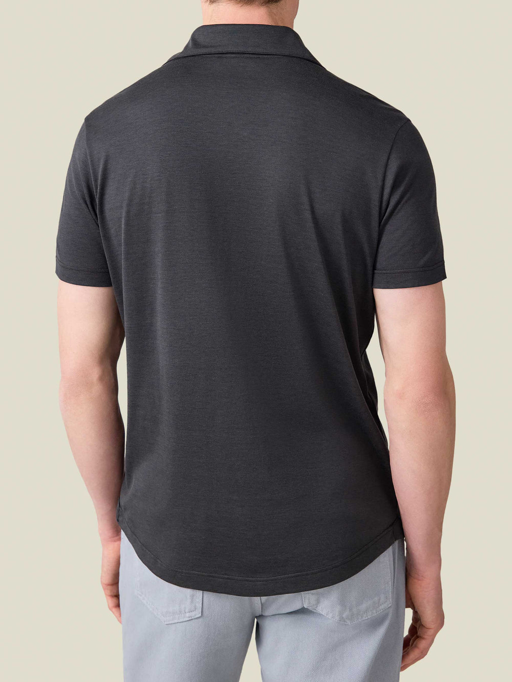 Back view of a man wearing the Charcoal Grey Short-Sleeved Silk-Cotton Polo, showing the rounded hem and relaxed fit.