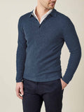 A man models the Atlantic Blue Cashmere Polo Sweater, layered over a white collared shirt and dark trousers.