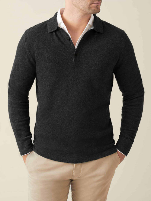 Front view of a man wearing a charcoal grey cashmere polo sweater layered over a white shirt and beige chinos.