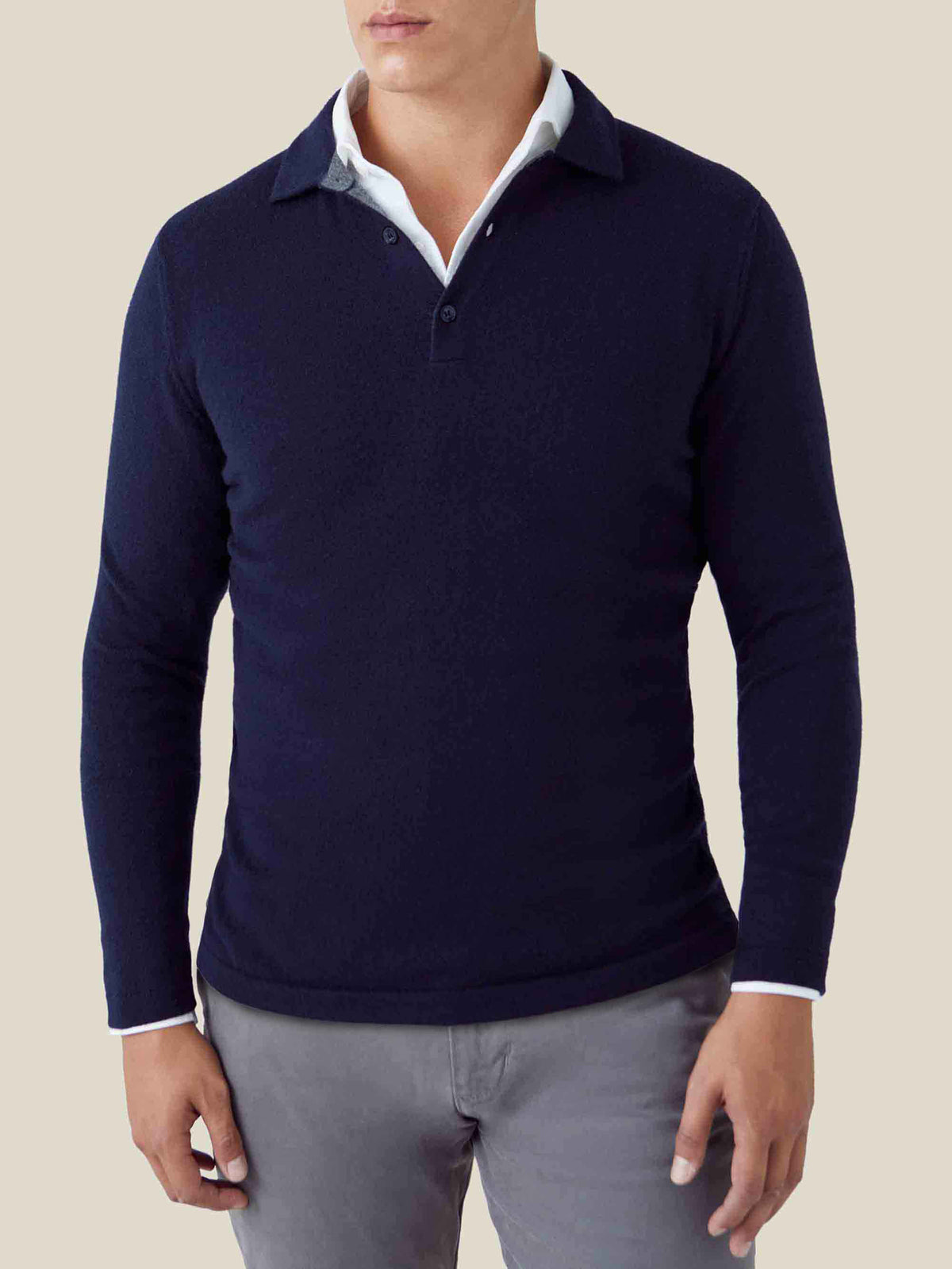A man wears the Midnight Blue Cashmere Polo Sweater layered over a white shirt and paired with grey trousers.