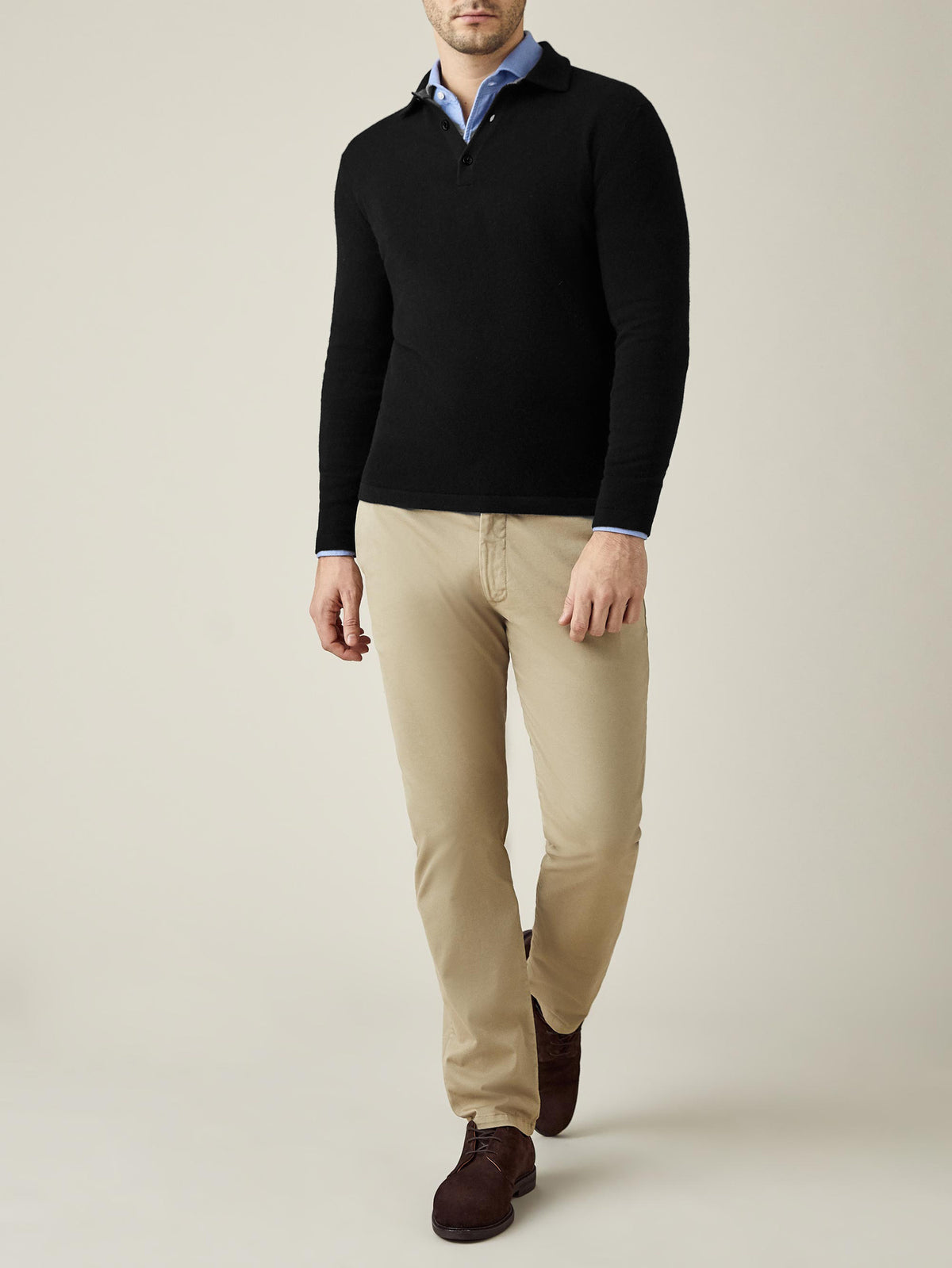 Front view of a model wearing the black Cashmere Polo Sweater, layered over a light blue shirt and styled with beige chinos.