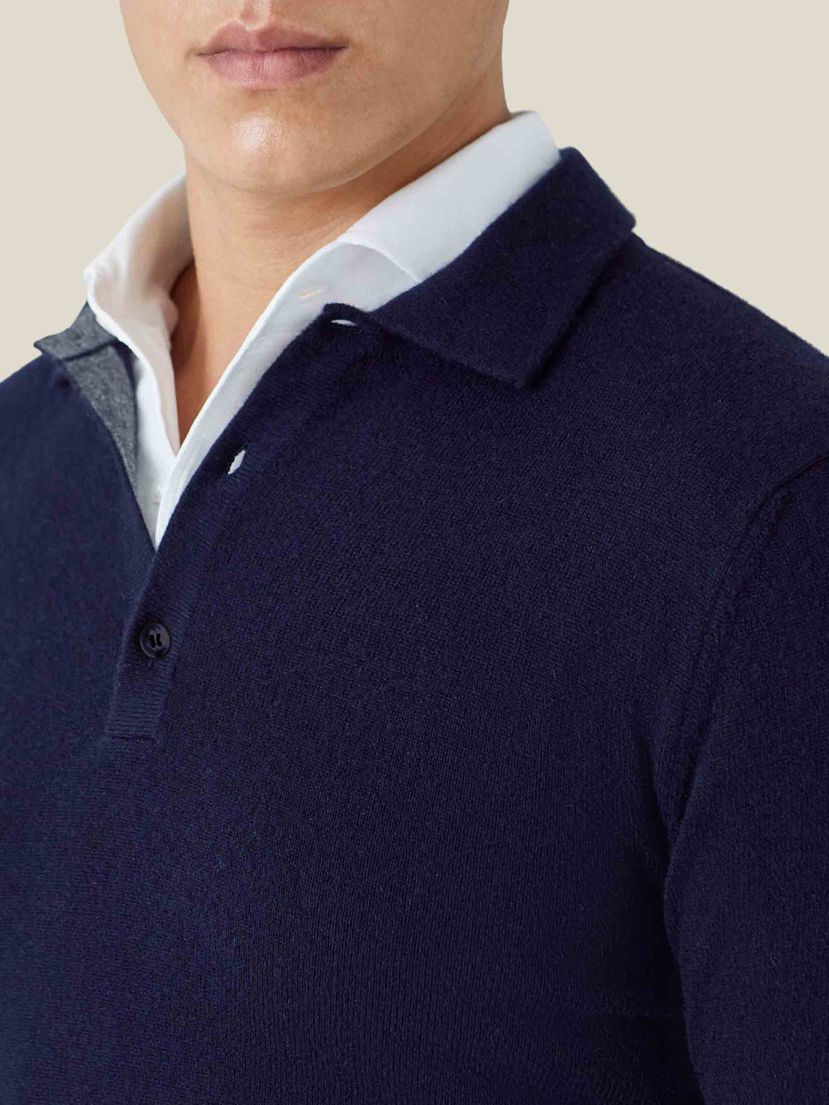 Close-up of the collar and placket of the midnight blue cashmere polo sweater, layered stylishly over a white shirt.