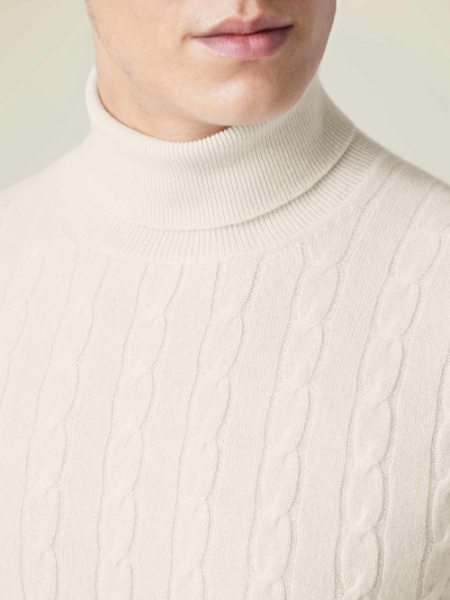 Close-up detail of the ivory Cable Knit Roll Neck, highlighting the luxurious cashmere and textured cable knit pattern.