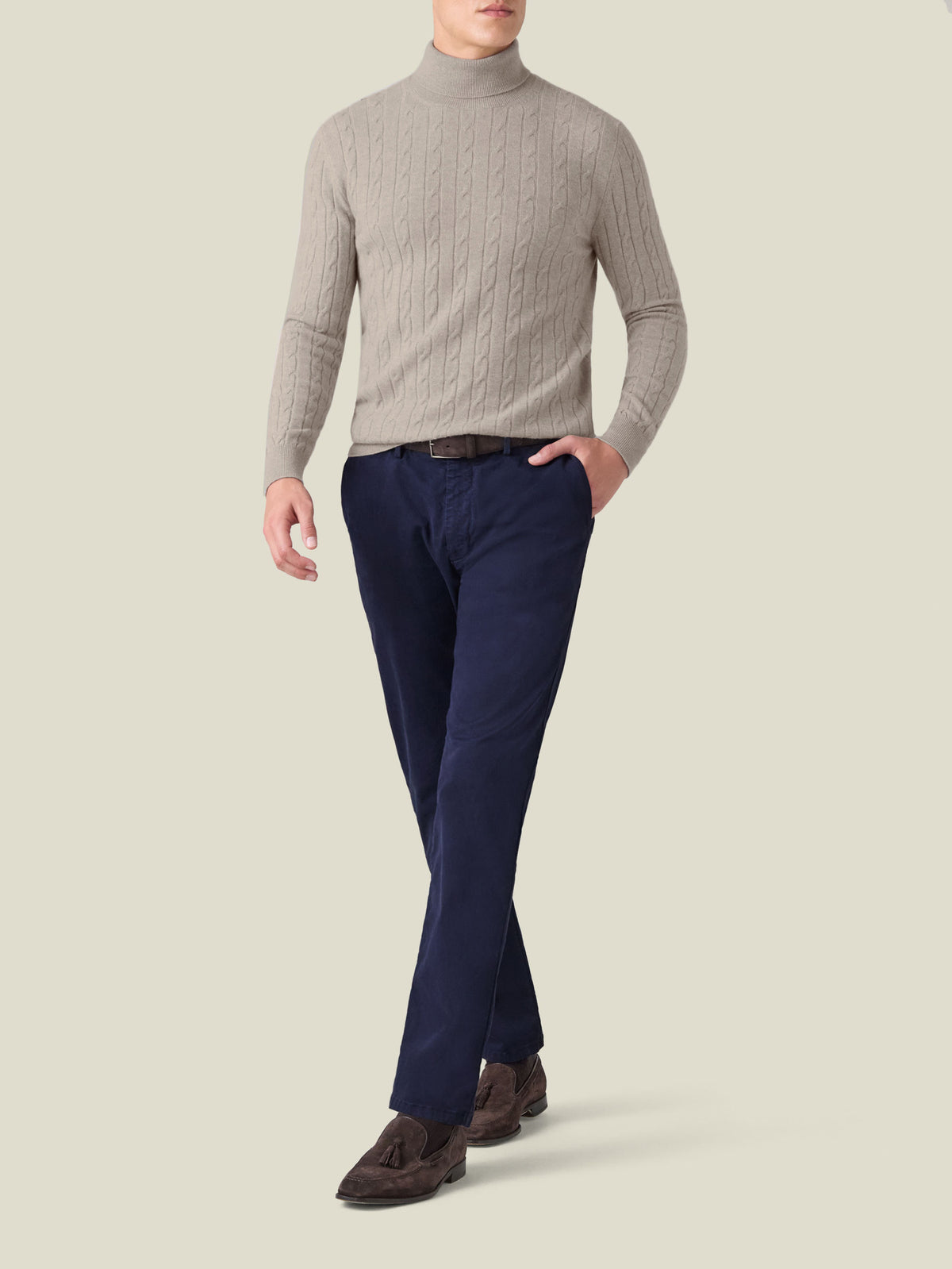 Front view of a model wearing the Luca Faloni Almond Cable Knit Roll Neck with navy trousers and brown loafers.