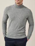 A man models the Luca Faloni Pure Cashmere Roll Neck in Dolomiti Grey, a versatile light grey sweater.