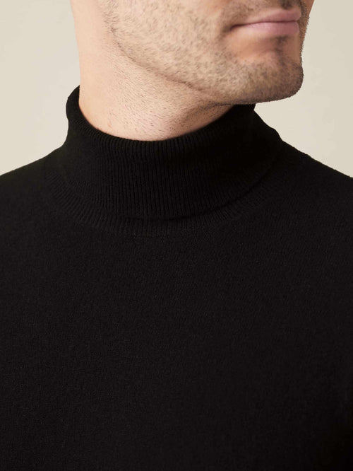 Close-up of a model wearing the Luca Faloni black cashmere roll neck, highlighting the finely ribbed collar and soft fabric.