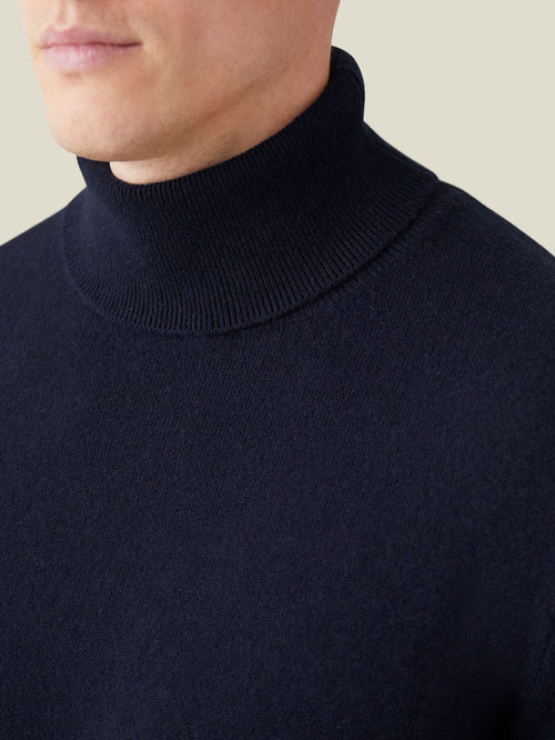 A close-up of a man wearing the Luca Faloni Cashmere Roll Neck in midnight blue, highlighting the ribbed neckline.