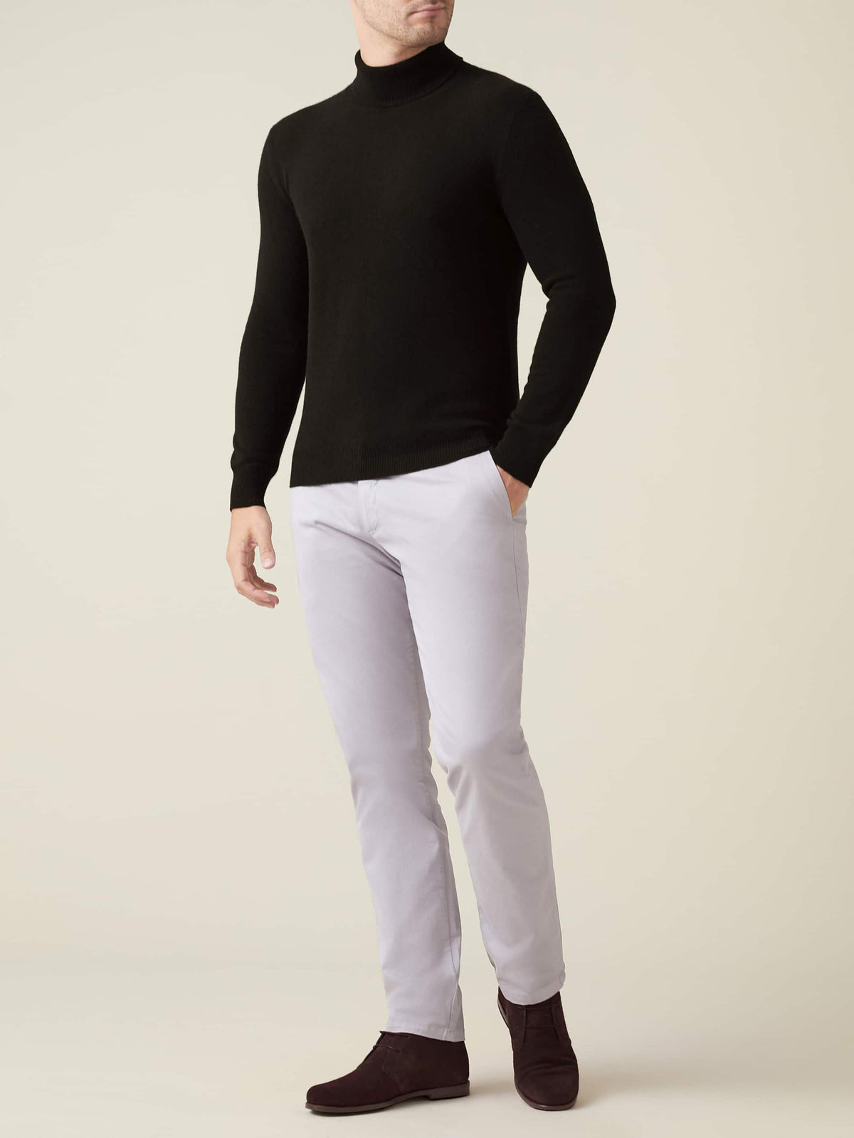 Model wears the Luca Faloni black cashmere roll neck with light grey trousers and dark suede boots.