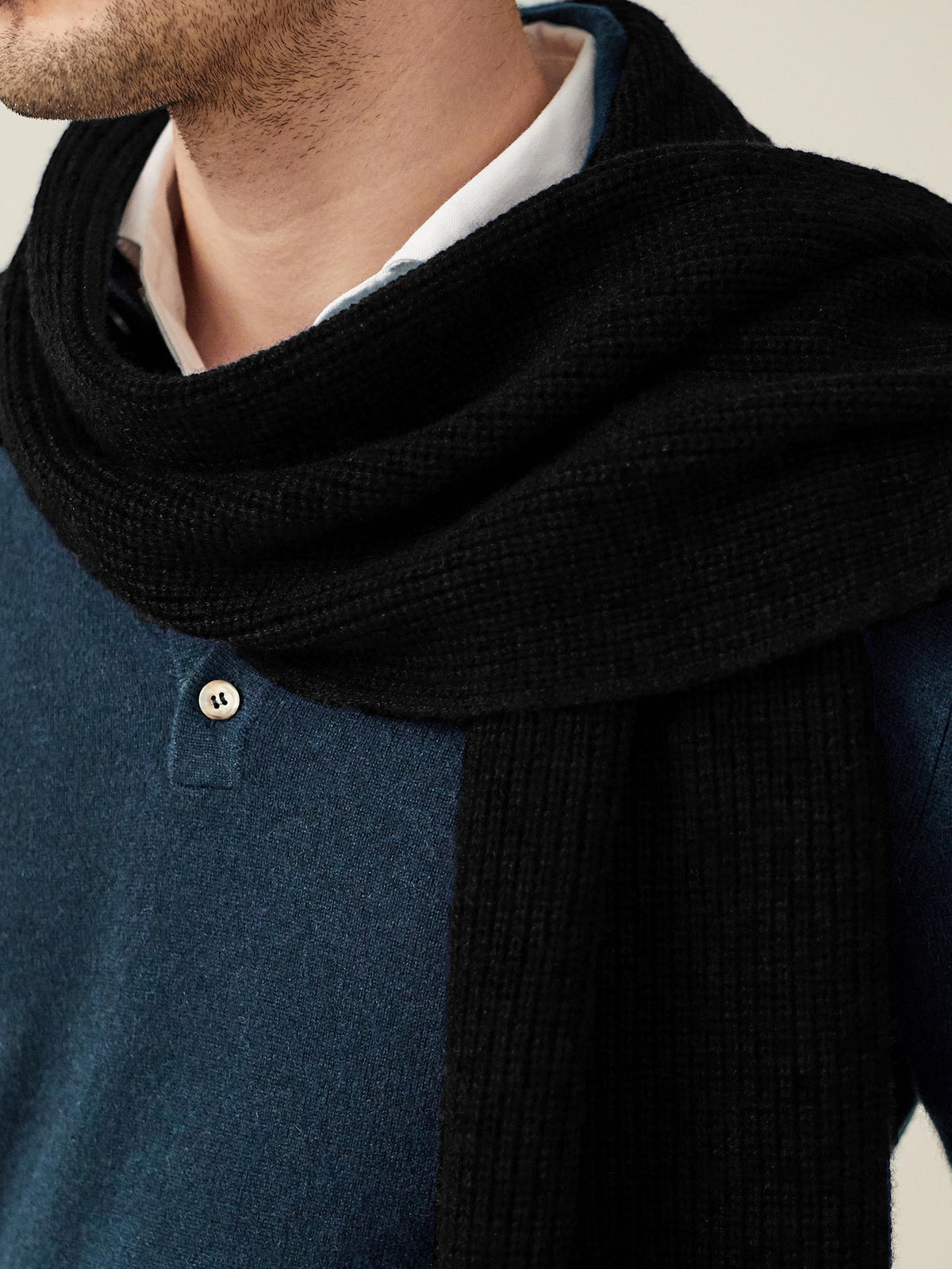 A close-up of a model wearing the Luca Faloni Black Chunky Knit Cashmere Scarf, highlighting its thick, ribbed texture.