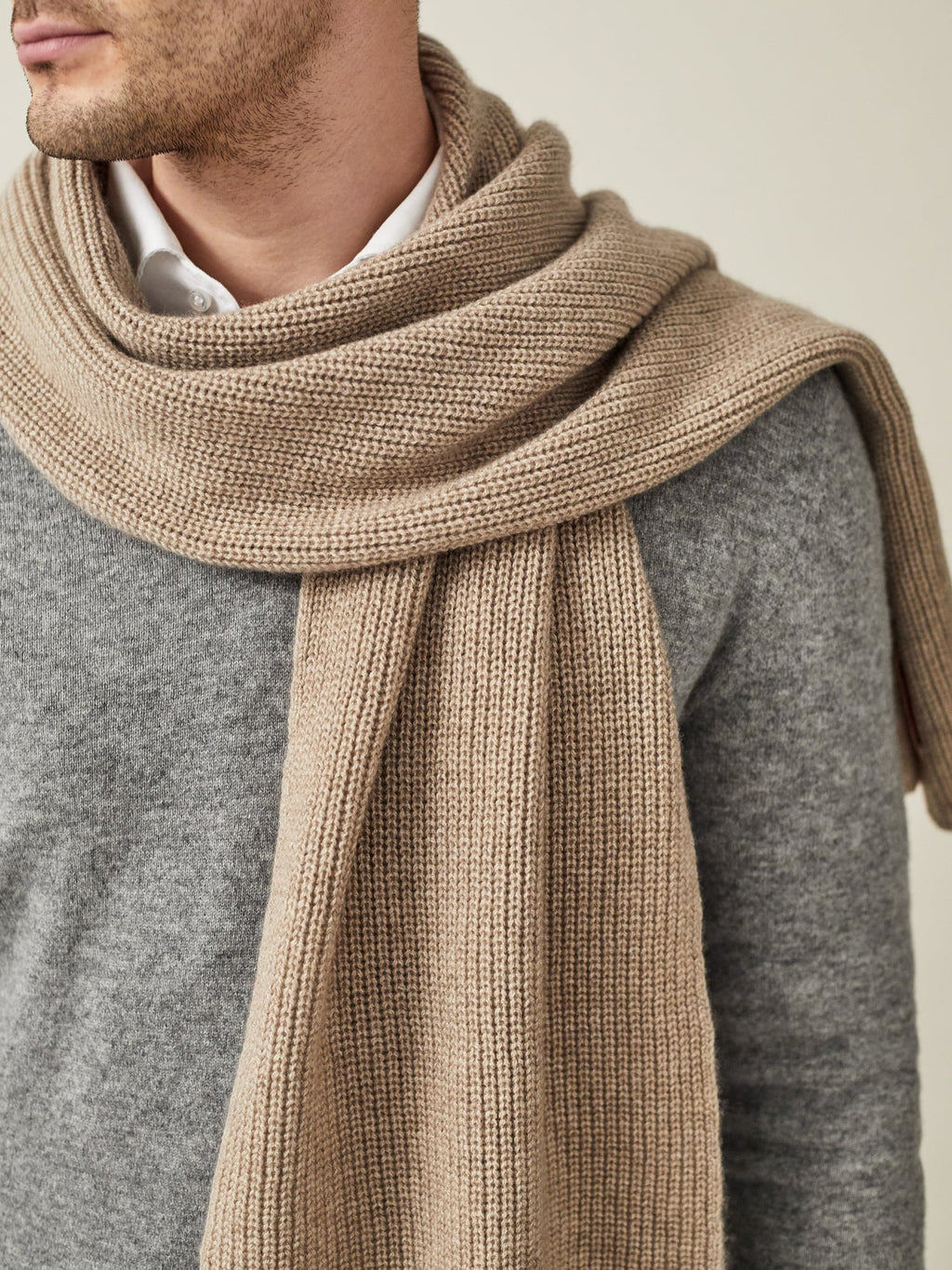 A close-up of a man wearing the Camel Beige Chunky Knit Scarf, styled over a grey jumper and white shirt.