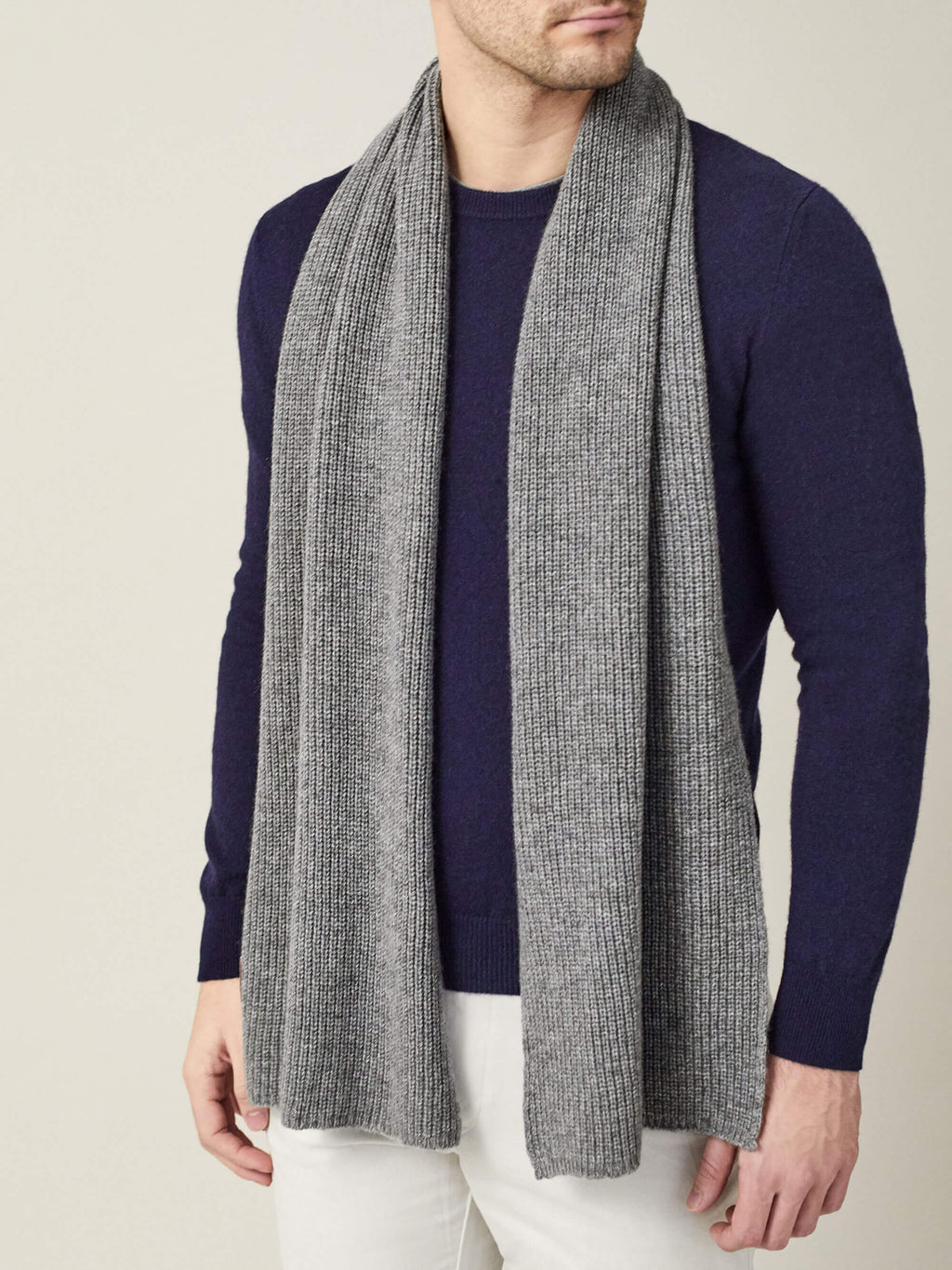 A model wearing the Luca Faloni Chunky Knit Cashmere Scarf in Dolomiti Grey over a navy sweater.