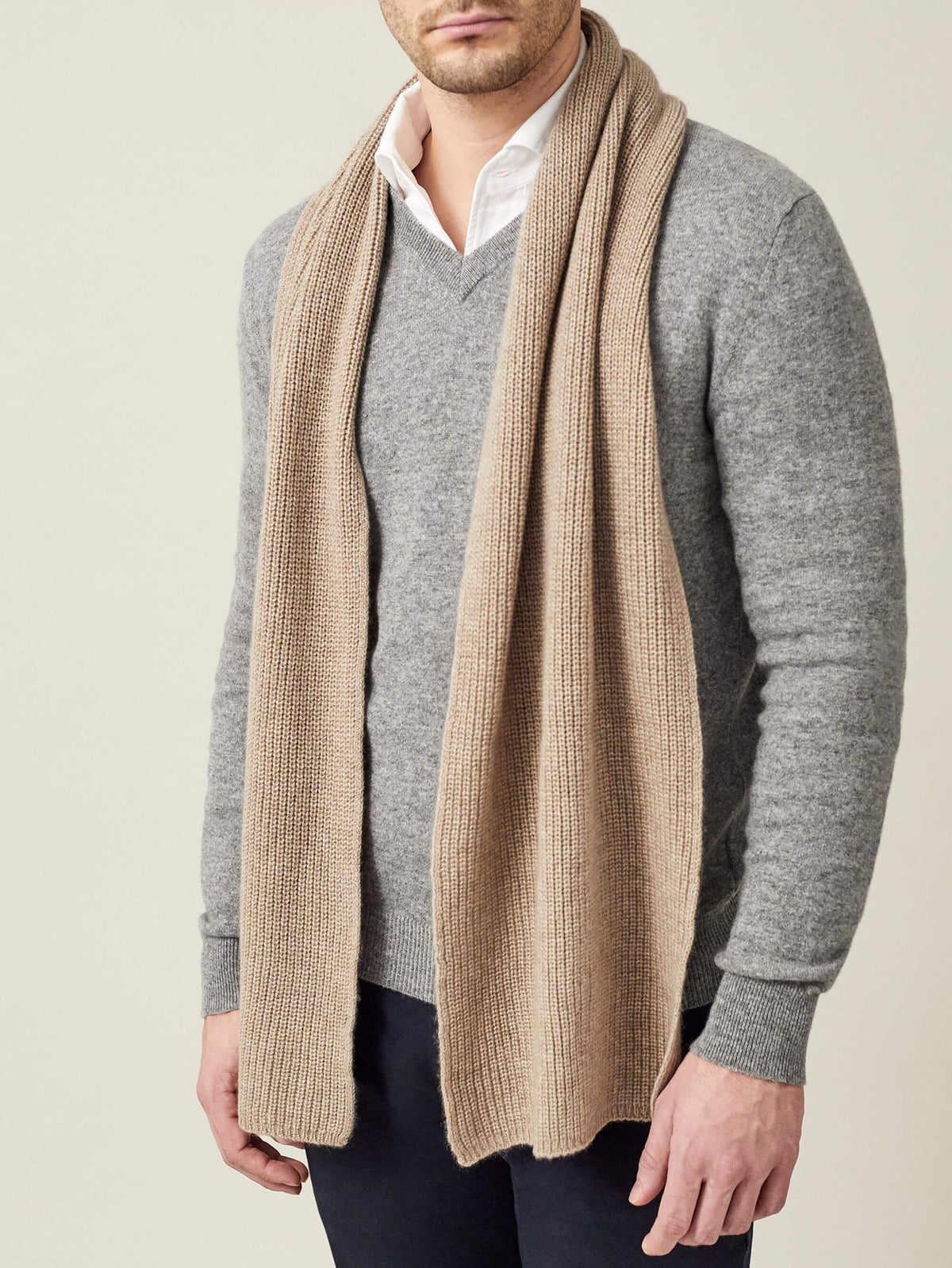 A front view of a model wearing the Camel Beige Chunky Knit Cashmere Scarf over a grey sweater and white collared shirt.