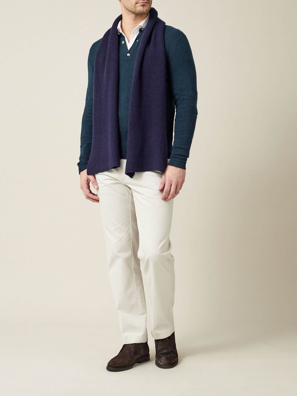 Full view of a model wearing the Midnight Blue Chunky Knit Cashmere Scarf over a teal jumper and white trousers.