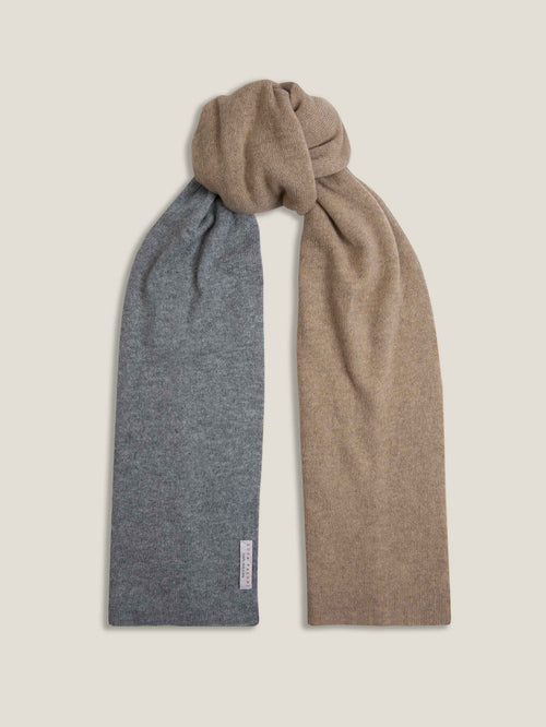 A Luca Faloni double-faced cashmere scarf in grey and brown, tied to show its contrasting sides against a light background.