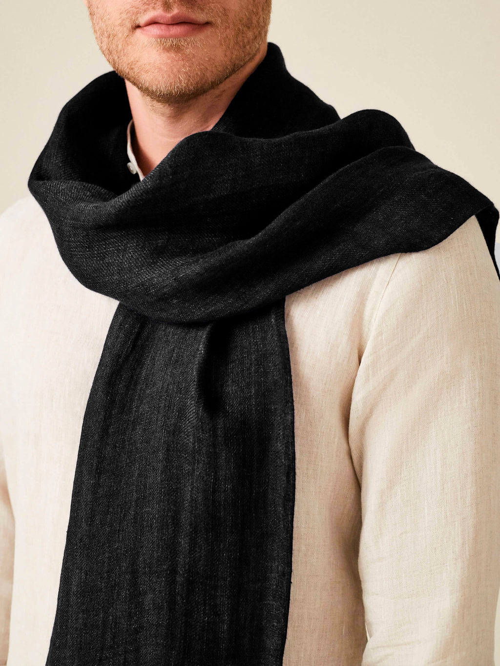 A close-up of a model wearing the Luca Faloni Black Linen Scarf, highlighting the fabric's texture.