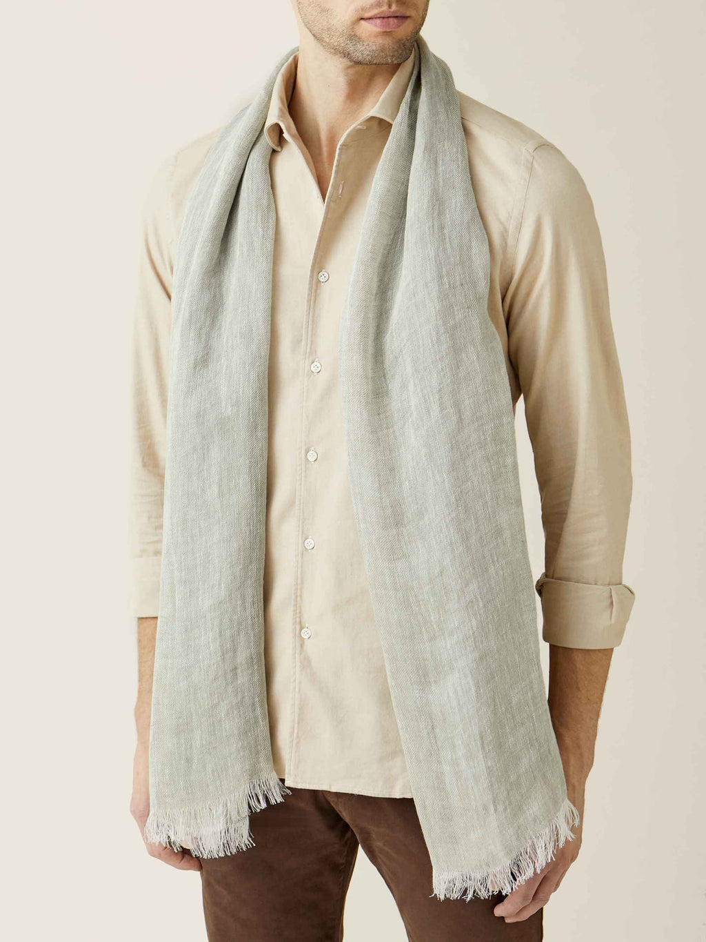 A model wears the Luca Faloni Khaki Green Linen Scarf draped around his neck over a beige button-down shirt.