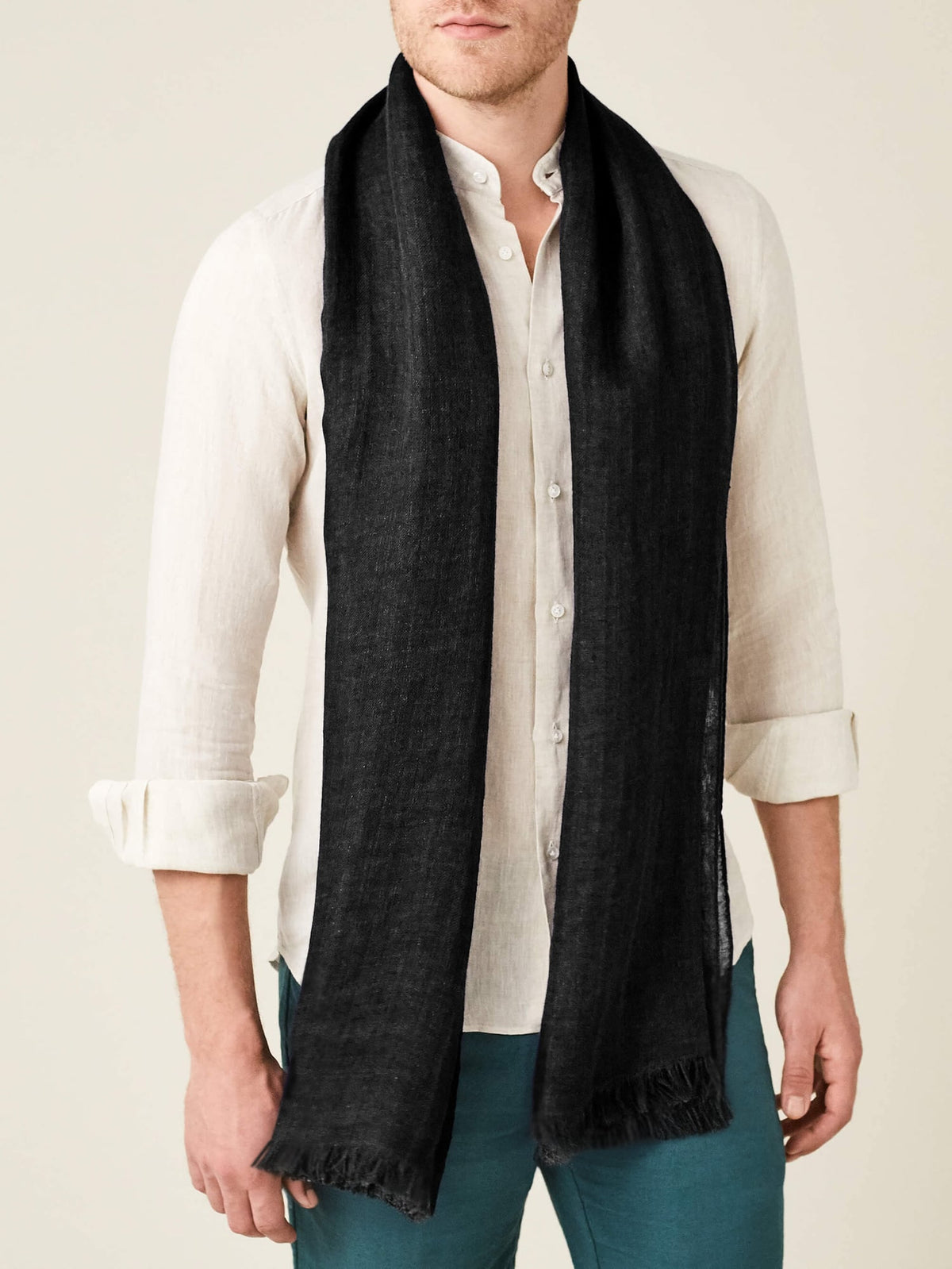 A front view of a model wearing the Luca Faloni Linen Scarf in Black with an off-white linen shirt.
