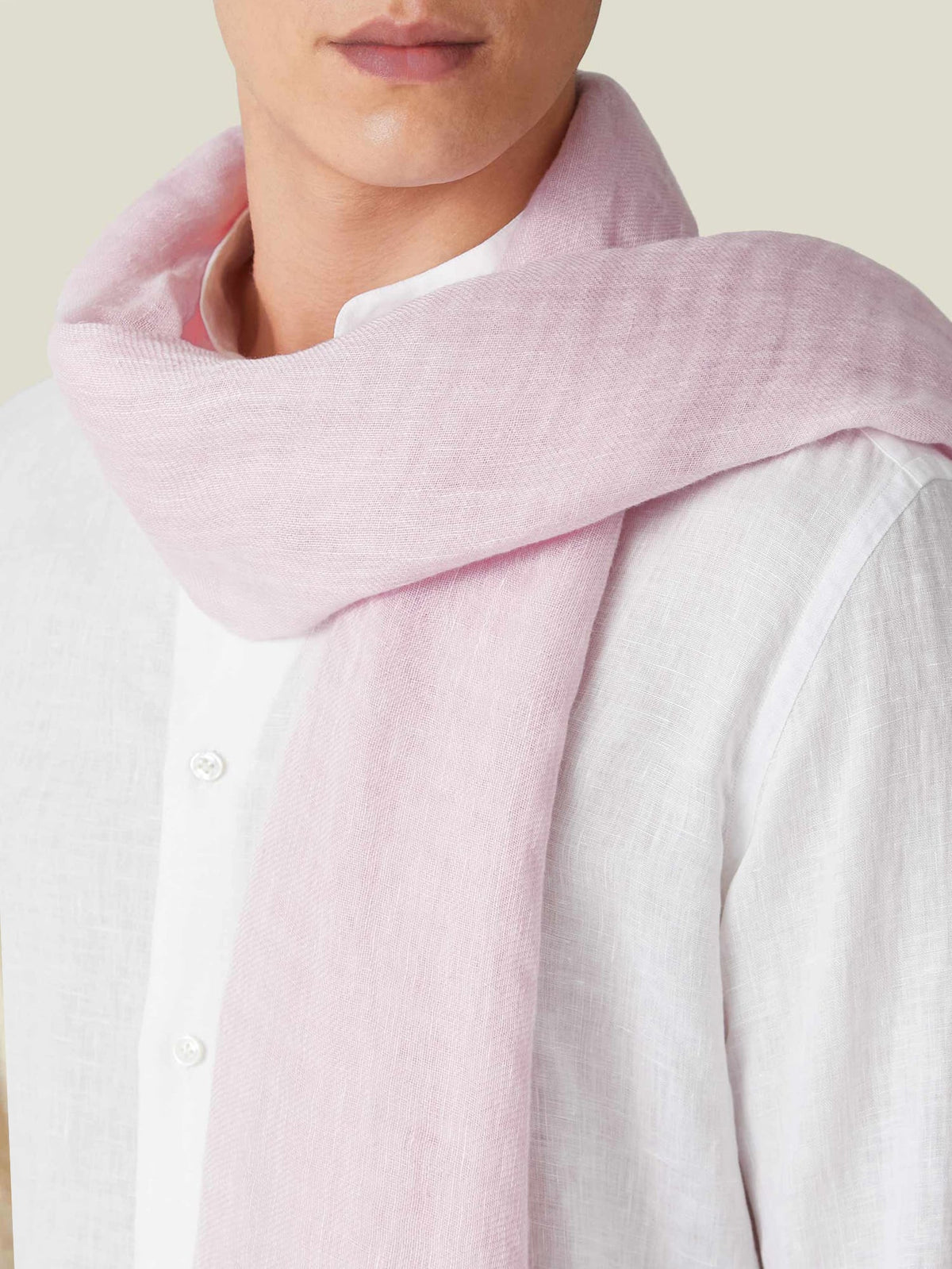Model wears the Luca Faloni light pink linen scarf, shown in a close-up to highlight the texture against a white shirt.