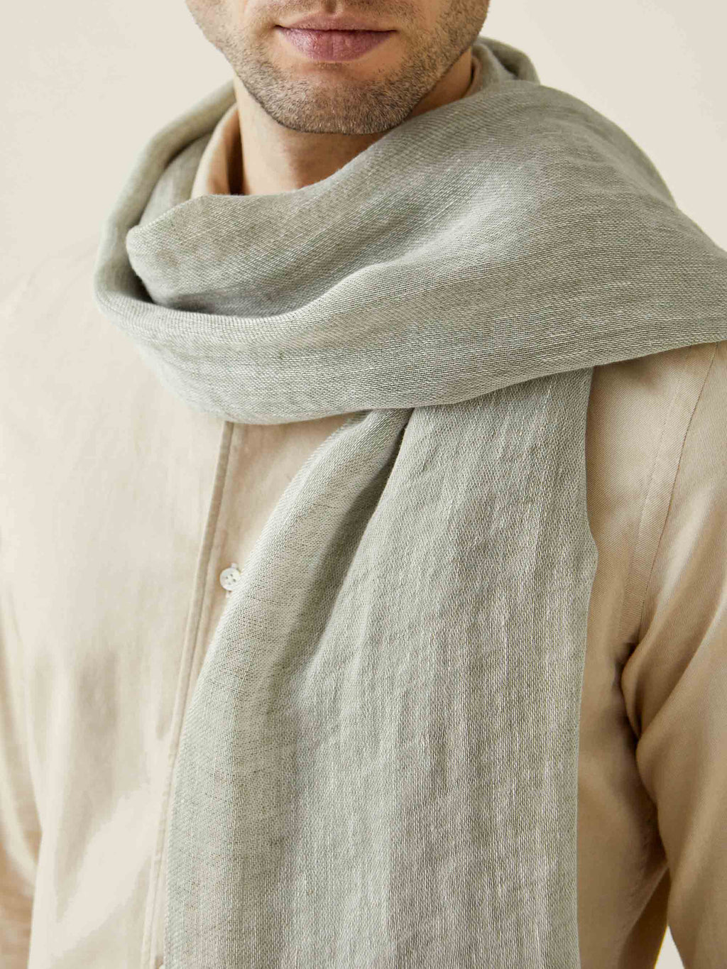 Close-up of a man wearing the Luca Faloni Khaki Green Linen Scarf, highlighting the soft texture and drape of the fabric.