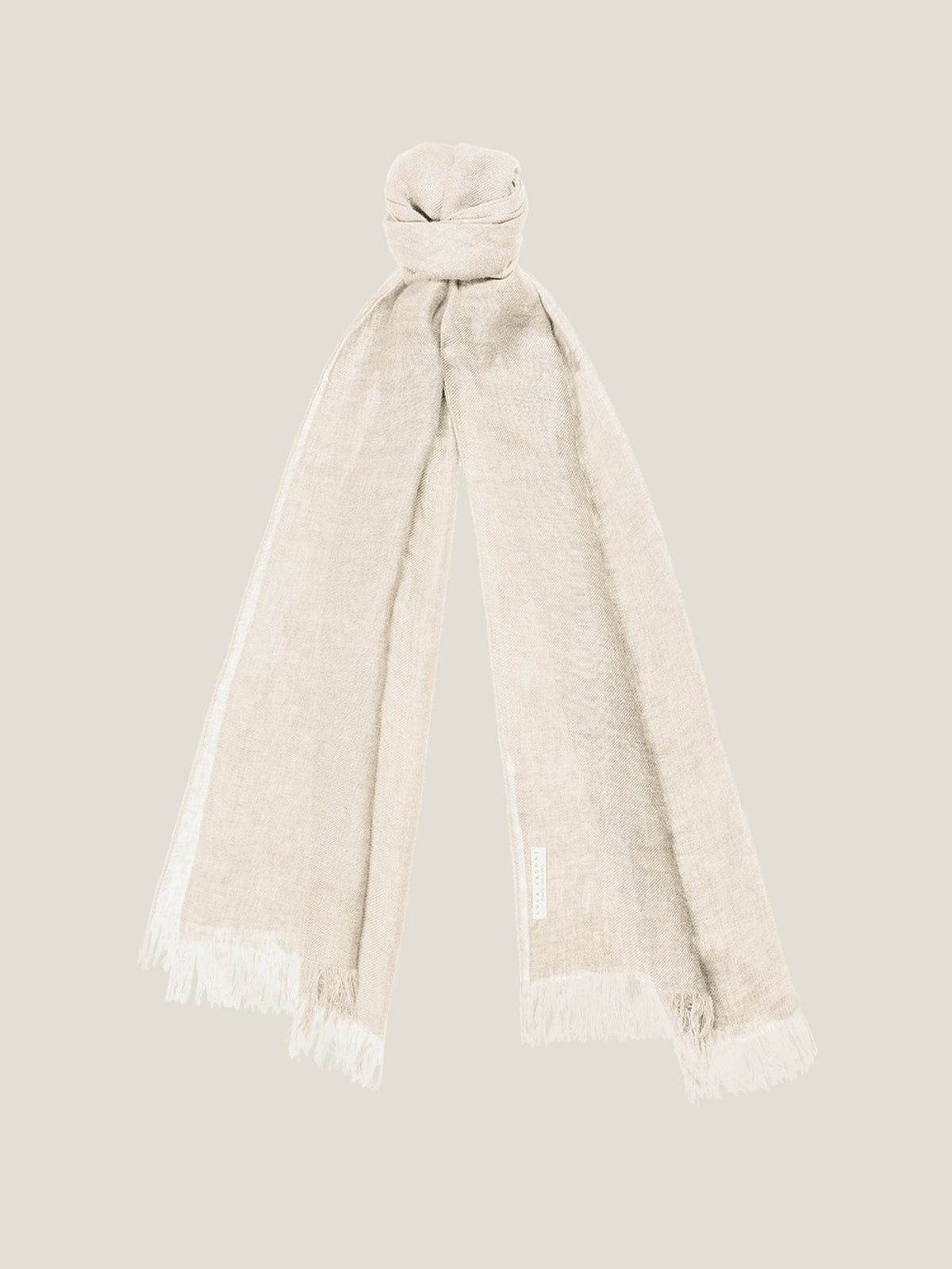 A sand-coloured linen scarf from Luca Faloni, tied in a knot, showing its lightweight fabric and fringed ends.