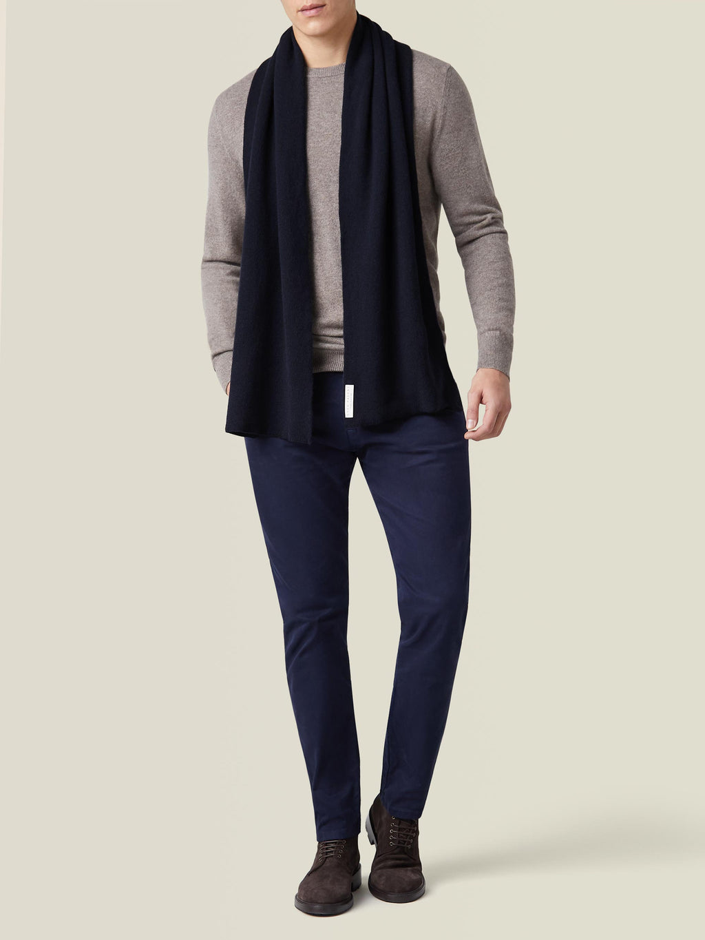 A model wearing the Luca Faloni Midnight Blue Cashmere Scarf, styled with a beige crew neck sweater and navy trousers.