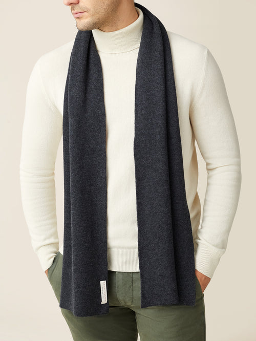 A front view of a model wearing the Luca Faloni Charcoal Grey Cashmere Scarf over a cream turtleneck sweater.