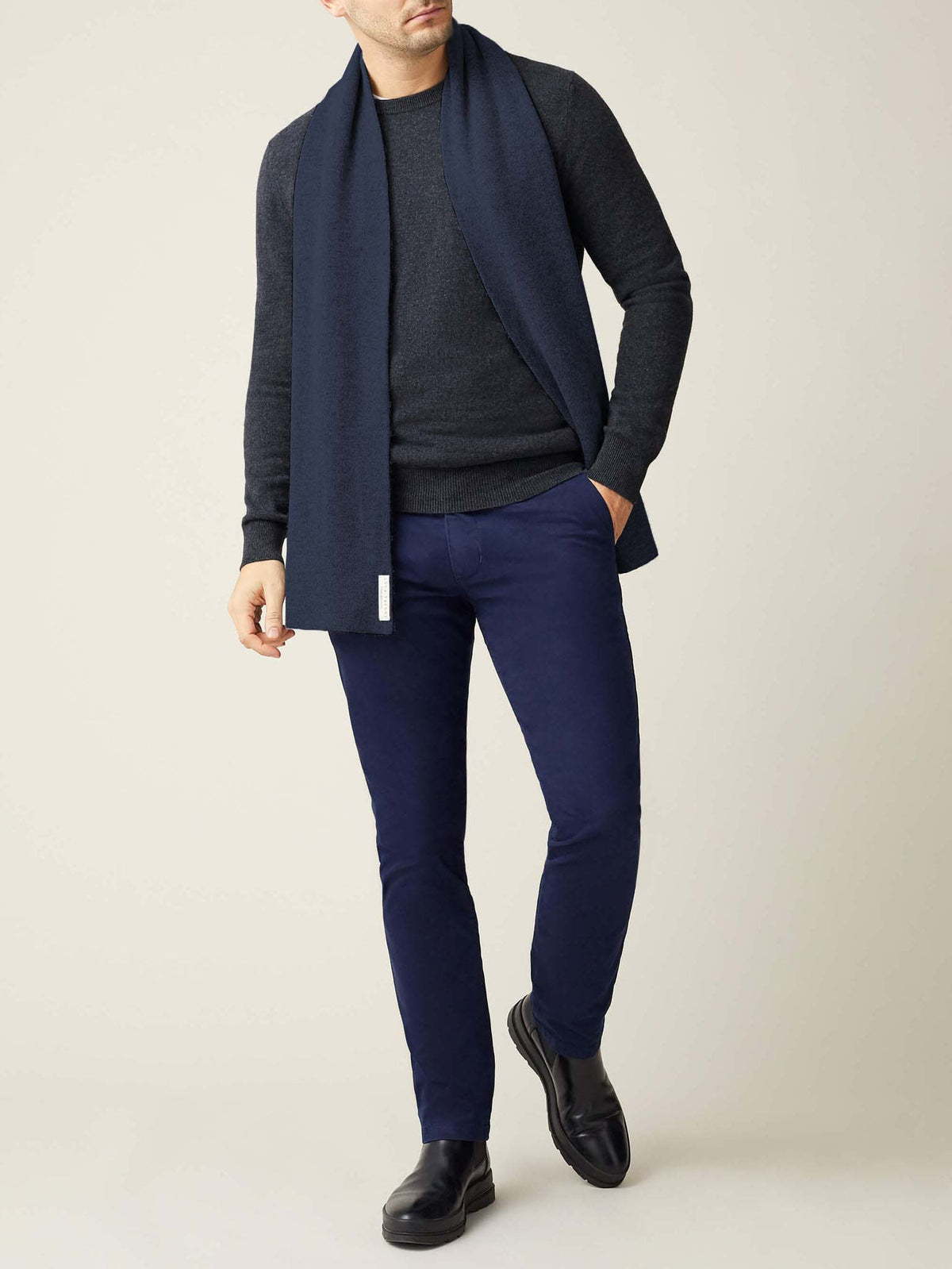A front view of a model wearing the Luca Faloni Cashmere Scarf in Atlantic Blue with a dark grey sweater and navy trousers.