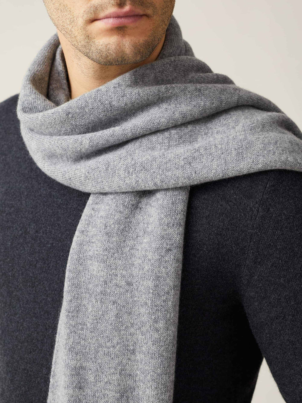 A close-up of a man wearing the Dolomiti Grey cashmere scarf, showing the soft texture of the knit against a dark sweater.