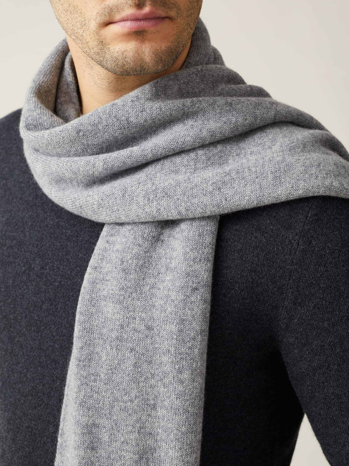 A close-up of a man wearing the Dolomiti Grey cashmere scarf, showing the soft texture of the knit against a dark sweater.