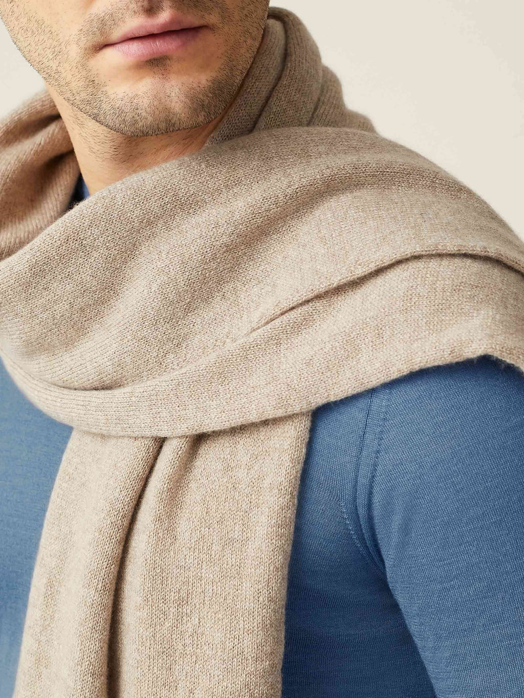 A close-up of a model wearing the Luca Faloni Cashmere Scarf in Camel Beige, showcasing its soft knit texture.