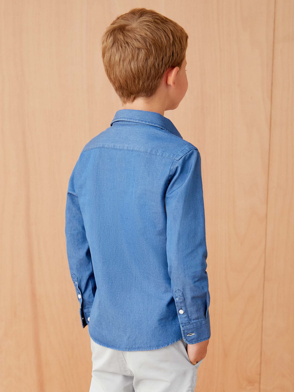 A young boy models the back of the Denim Junior Shirt in Classic Blue, showing the fit and yoke detail.
