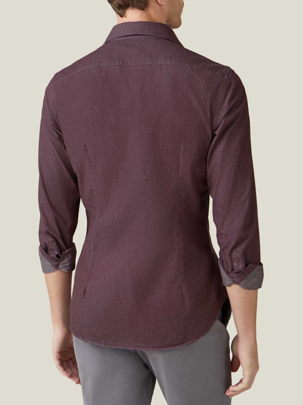 Back view of a model wearing the Luca Faloni Denim Shirt in burgundy, highlighting its tailored fit and rolled up cuffs.