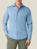 A man models the Luca Faloni light blue denim shirt, paired with olive green chinos.