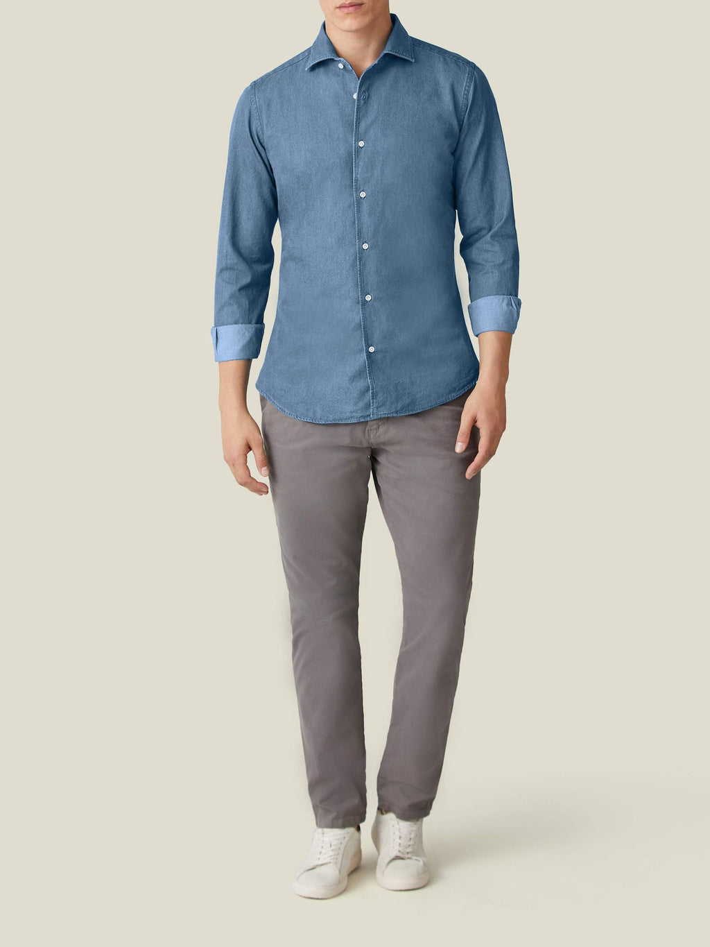 Model wears the Classic Blue Denim Shirt with sleeves rolled up, paired with grey trousers and white sneakers.