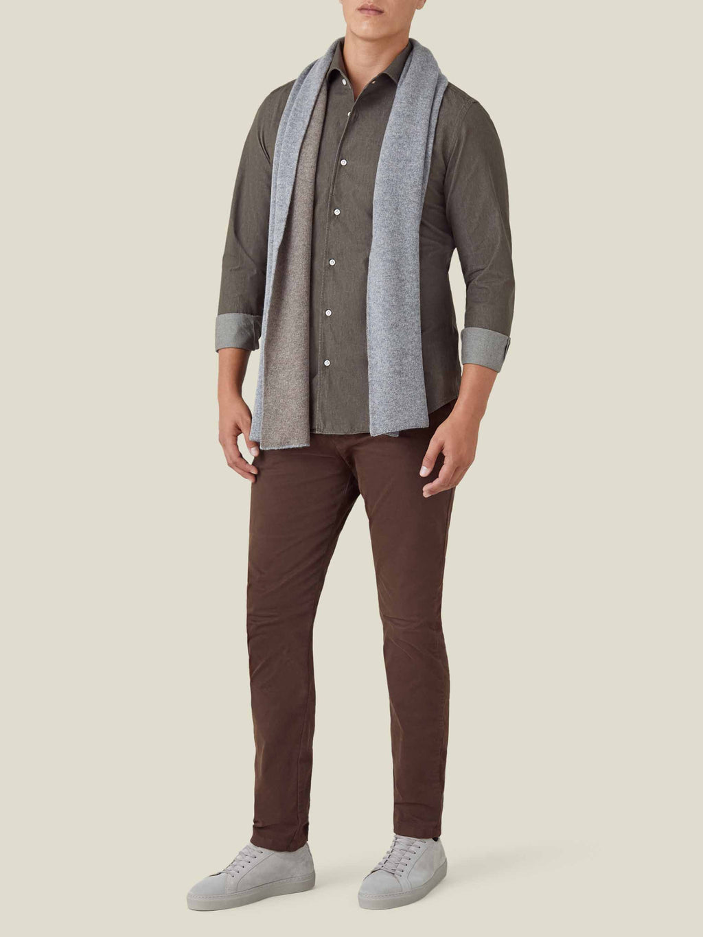 Full-length view of a model wearing a military green Denim Shirt, styled with brown trousers, a grey scarf, and trainers.