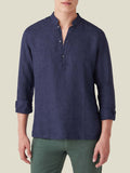 A model wears the navy blue Forte Linen Shirt with a band collar and sleeves rolled up, shown from the front in a studio.