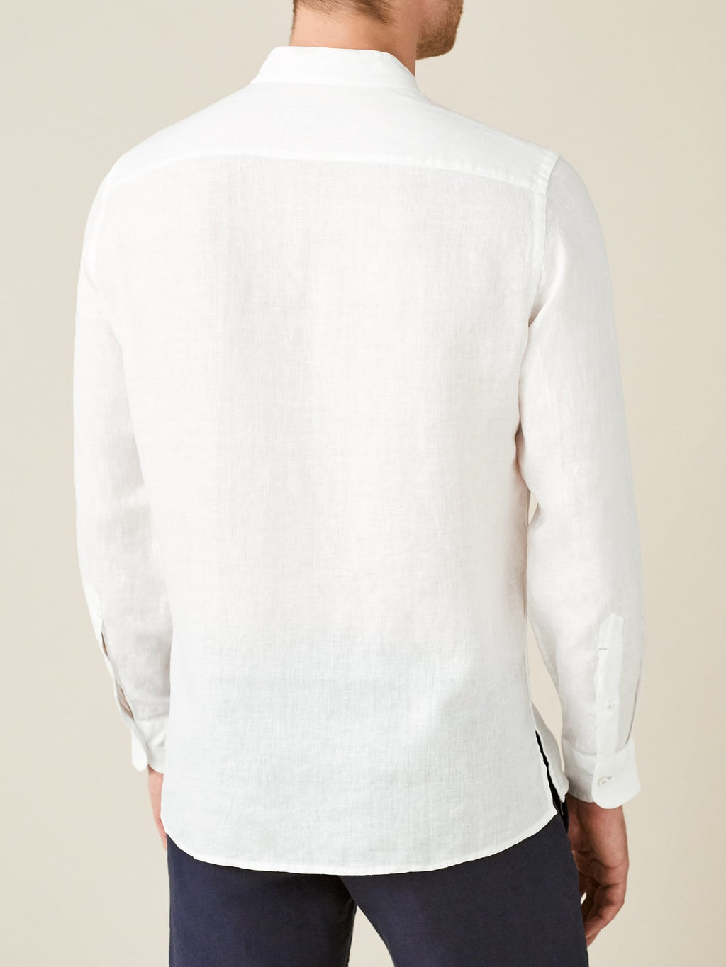 Back view of a model wearing the white Forte Linen Shirt, showcasing the shirt's relaxed fit and band collar.
