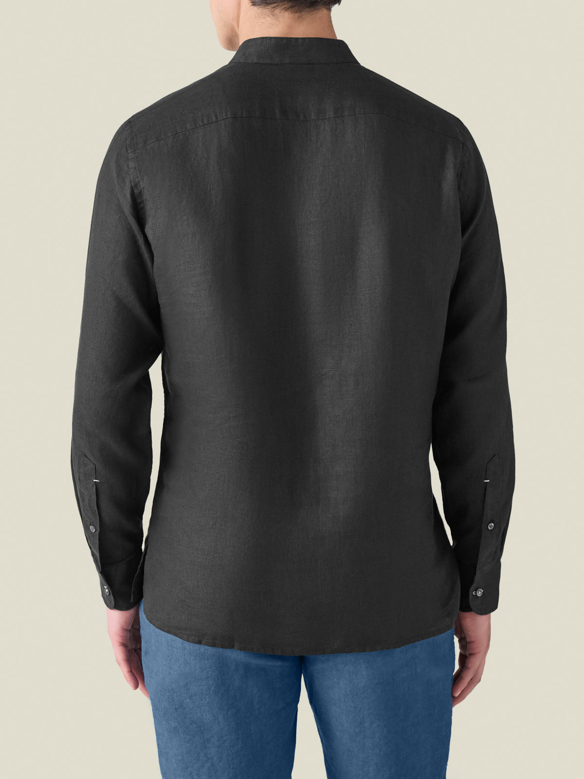 Rear view of a model wearing the black Forte Linen Shirt, showing the band collar and fit.