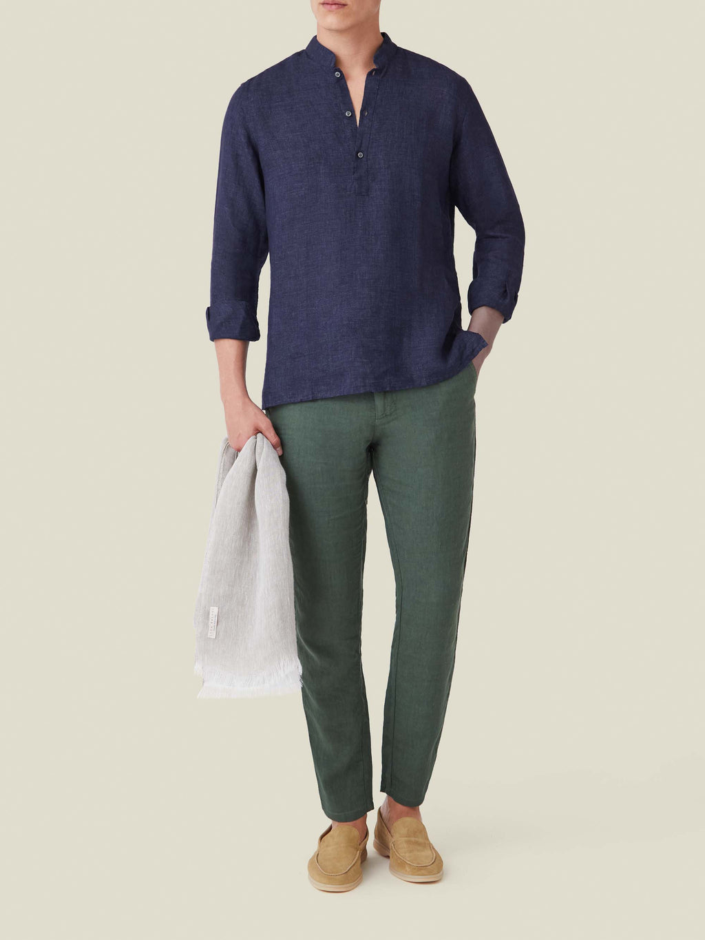 A model wears the navy blue Forte Linen Shirt with a band collar, styled with green trousers and tan loafers.
