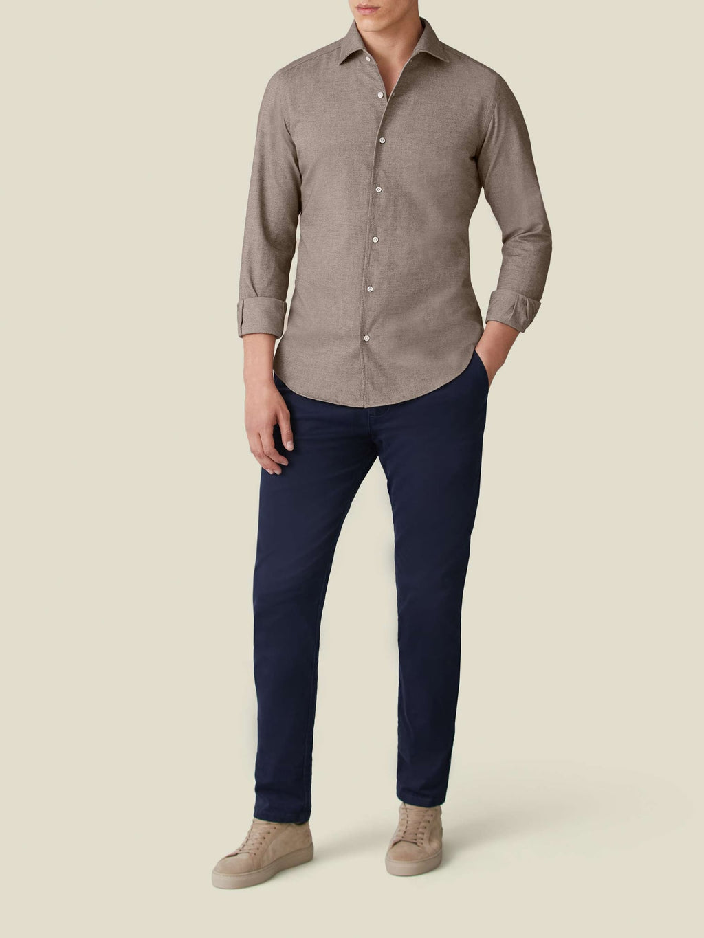 A man models the Luca Faloni Brushed Cotton Shirt in Nocciola Brown, paired with navy trousers and tan suede sneakers.