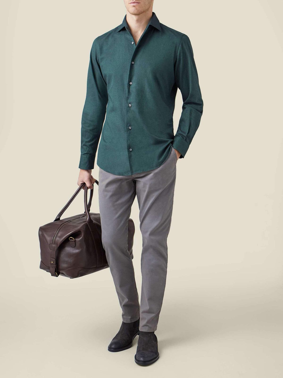 Model wears the Luca Faloni Brushed Cotton Shirt in Forest Green, styled with grey trousers and holding a leather travel bag.