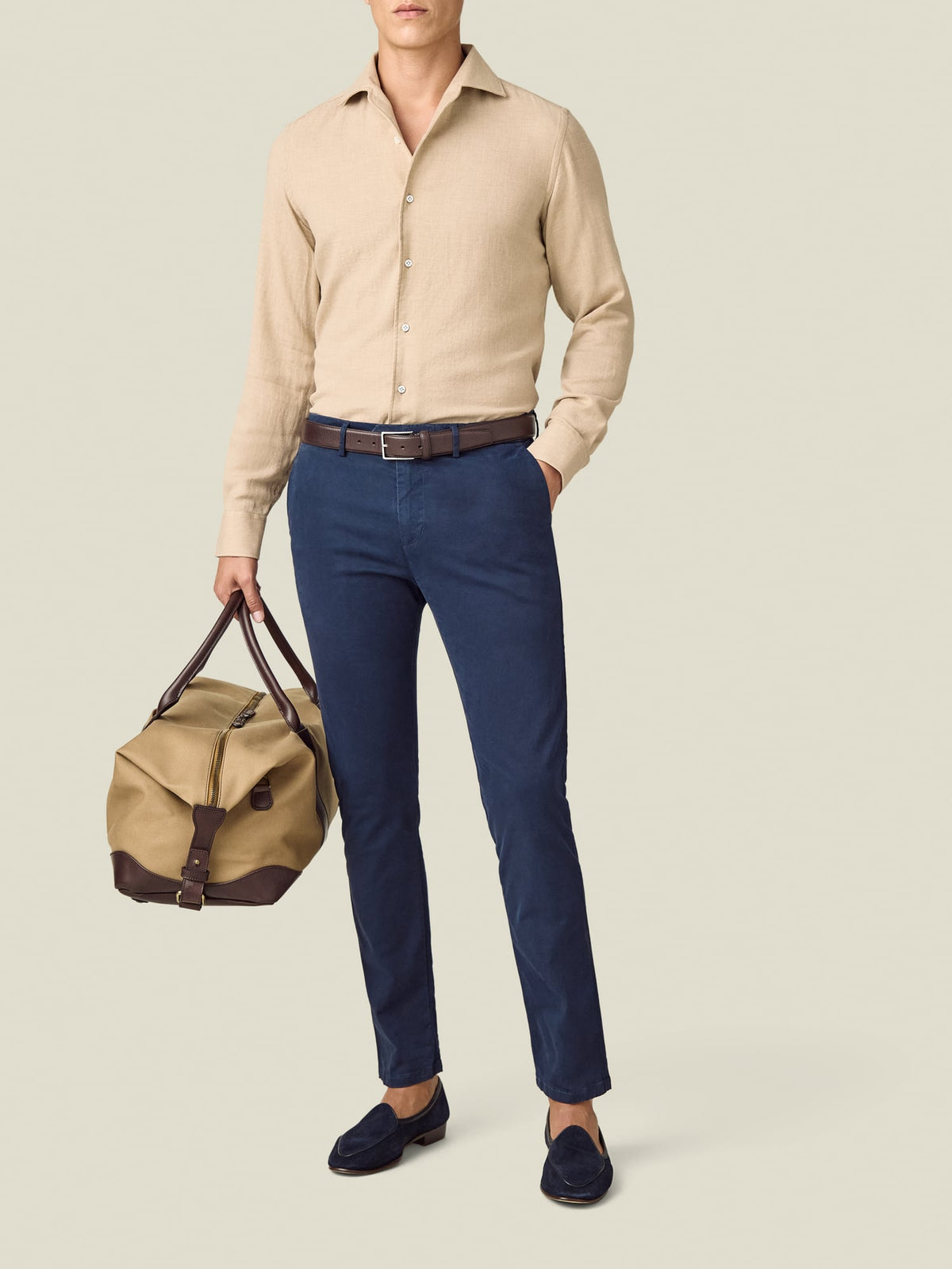 Front view of a model wearing the Luca Faloni Sand Cashmere-Cotton Shirt, styled with navy trousers and a travel bag.