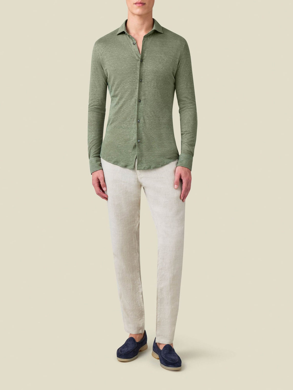 Front view of a model wearing the Linen Jersey Shirt in olive green, styled with light-coloured trousers and navy shoes.