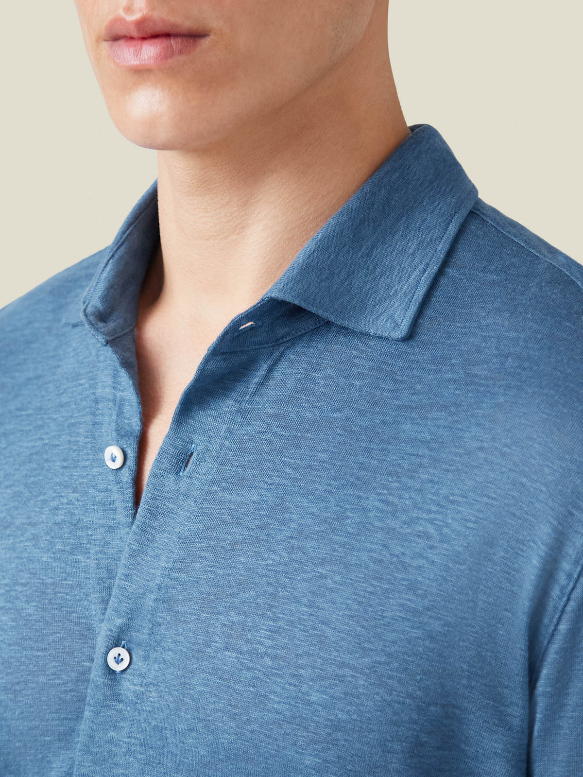 A close-up view of the steel blue linen jersey shirt's cutaway collar, placket, and soft fabric texture on a model.