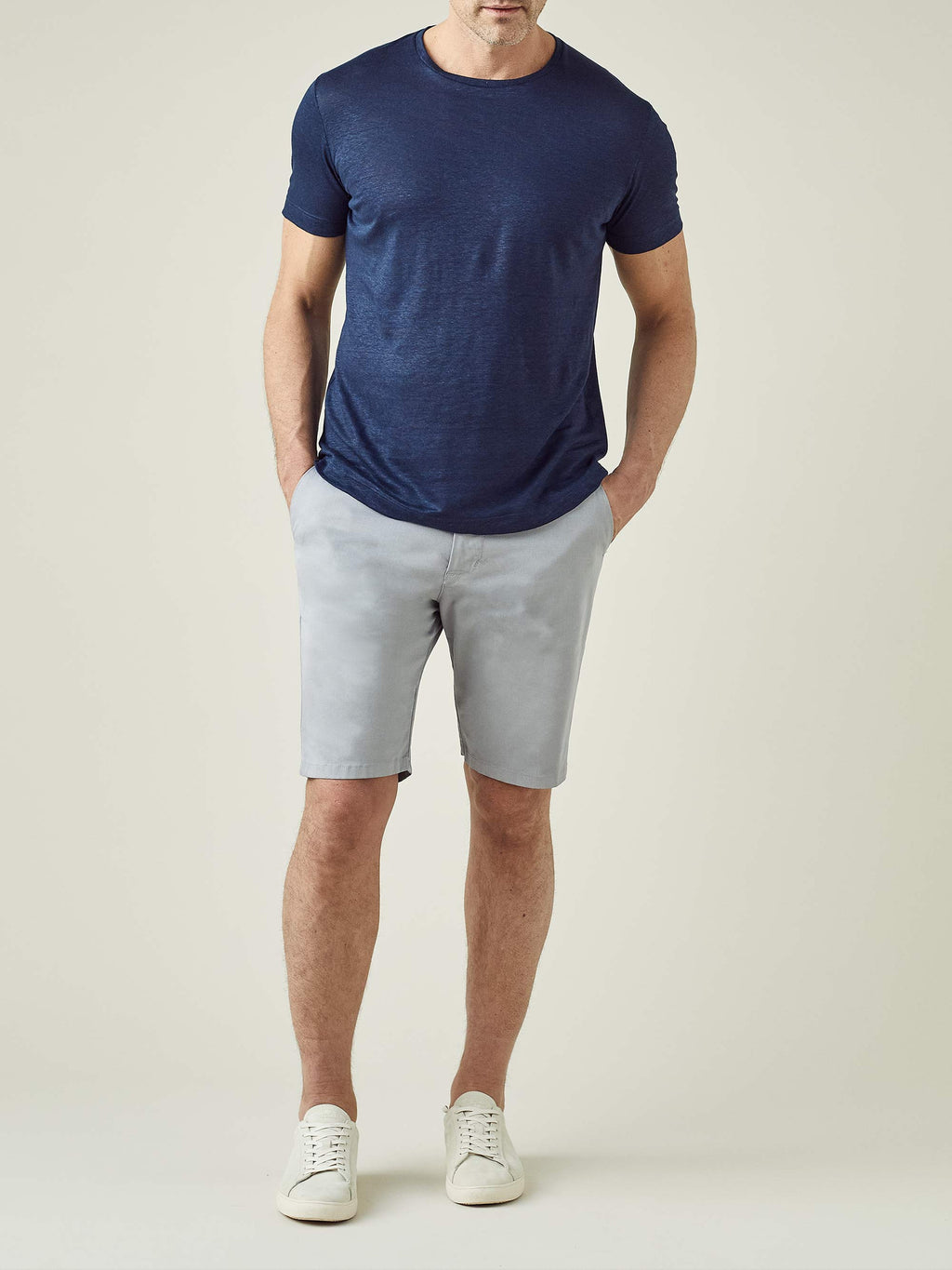 Full length shot of a model wearing Luca Faloni's Light Grey Cotton Shorts with a navy t-shirt and white sneakers.