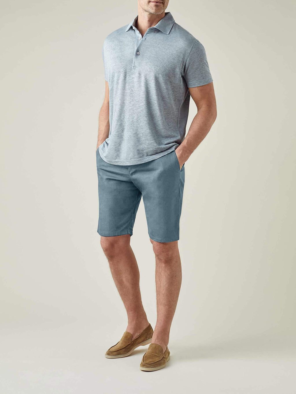 A model wears the Luca Faloni Light Blue Cotton Shorts with a grey polo shirt and tan suede loafers.